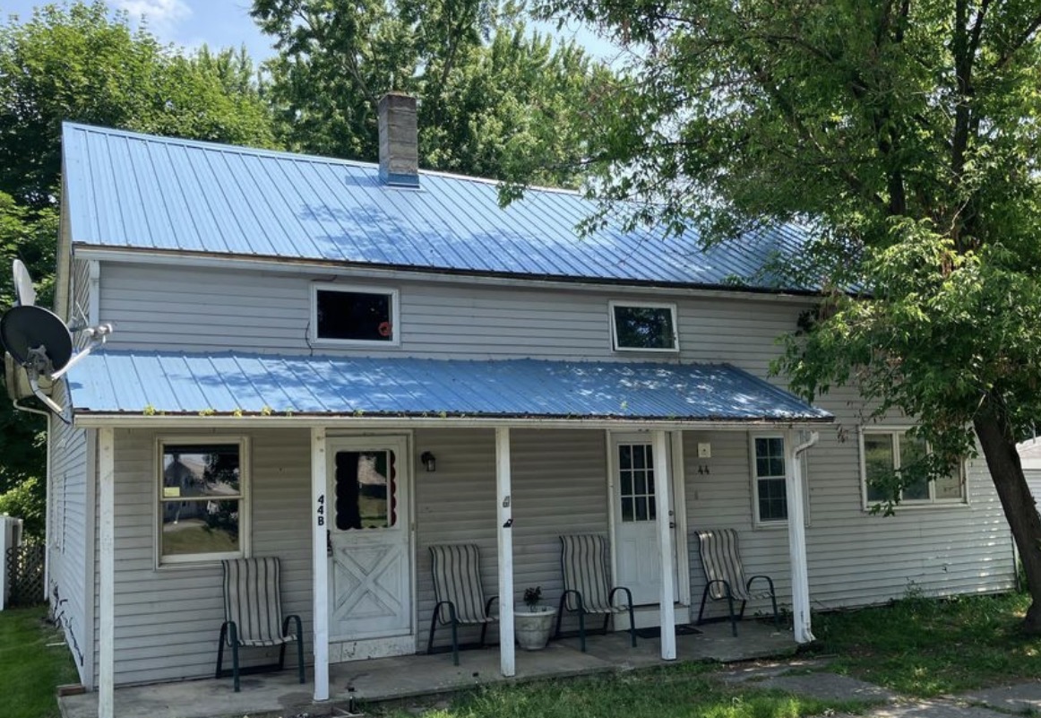 Two-story fix and flip investment property with blue roof funded in Stillwater, NY